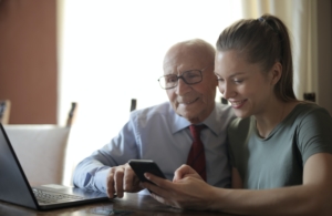 Positive senior man and smiling young woman watching