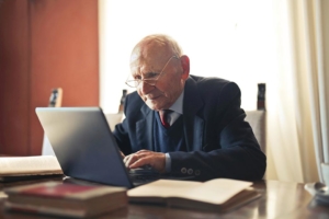 serious senior man in formal suit working on laptop