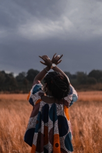 Woman in a field with hands raised